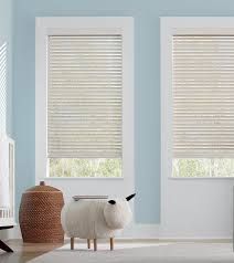 A room with two windows and a sheep sitting on the floor.