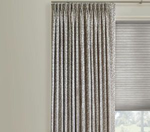 A pair of curtains hanging on a window next to a window with blinds.