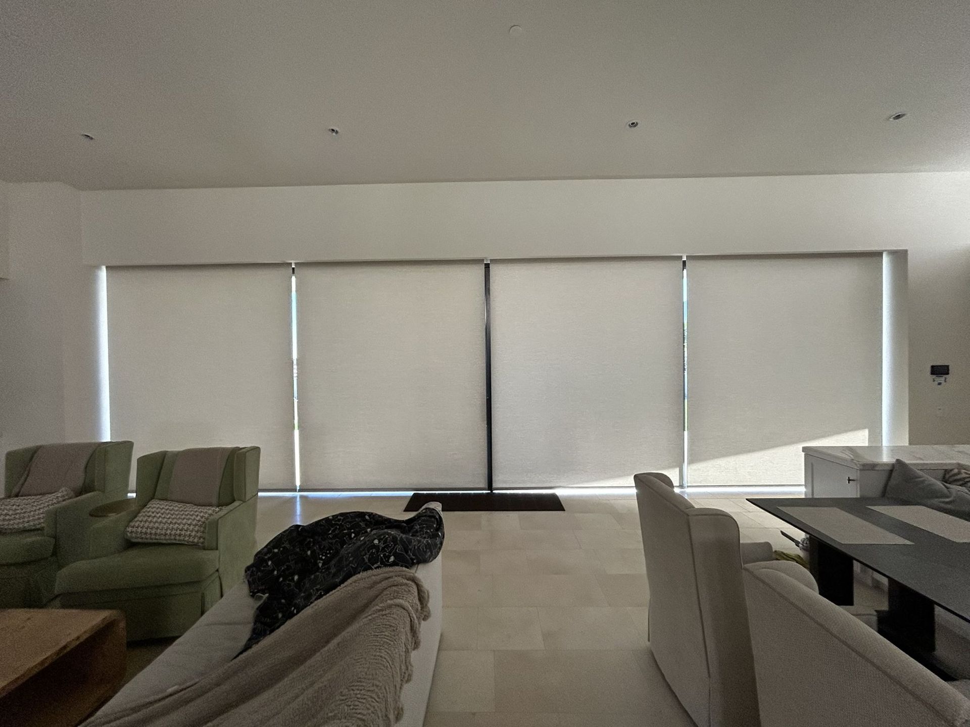 Motorized solar shades lowered across large living room windows