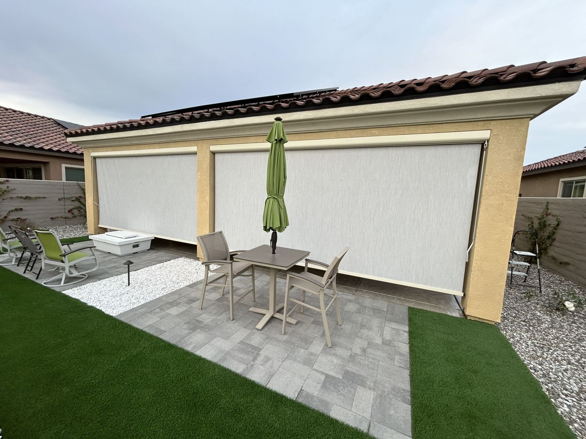 Exterior solar shades lowered around a backyard patio