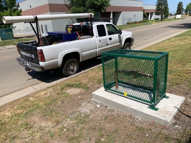 A white truck is parked on the side of the road next to a green trash can.