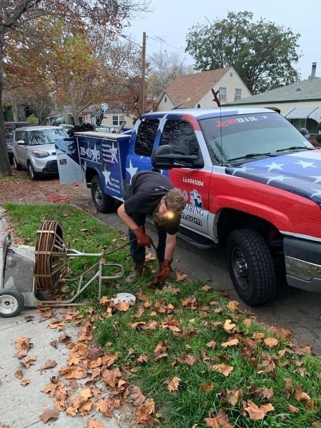 A man is working on a drain in front of a truck.