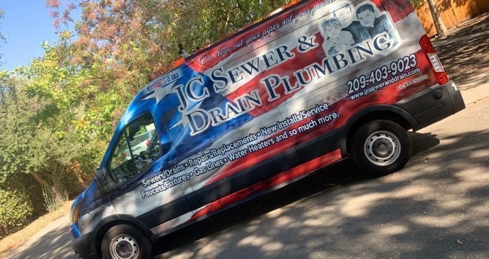 A drain plumbing van is parked on the side of the road.