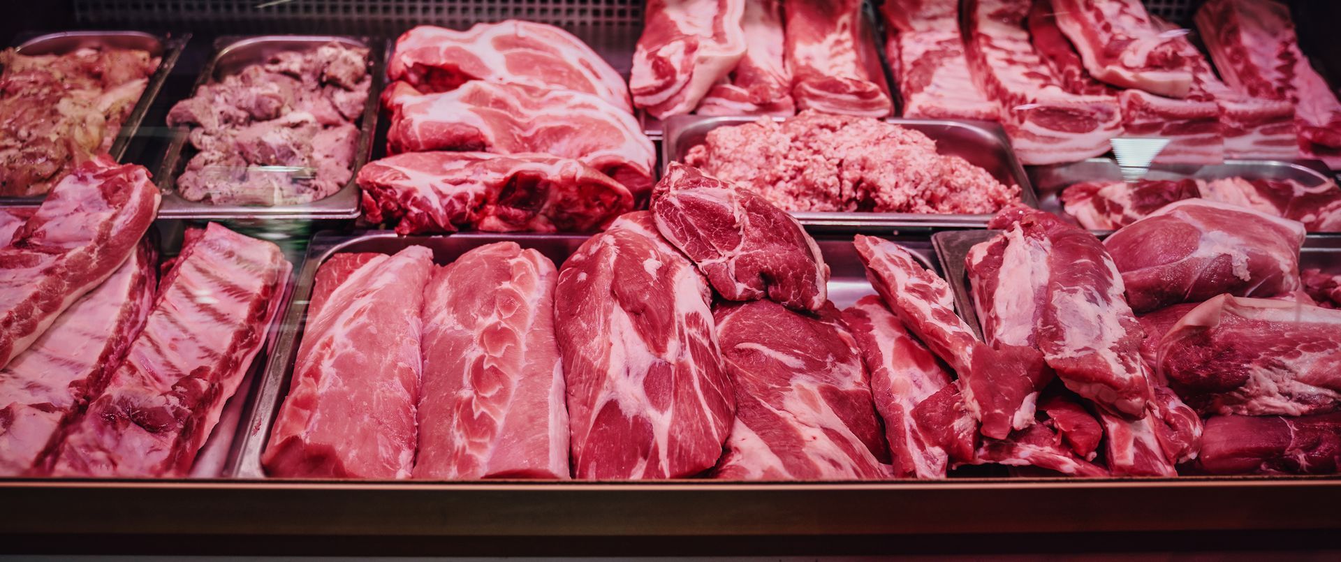 Butcher display case with assorted raw cuts of red meat