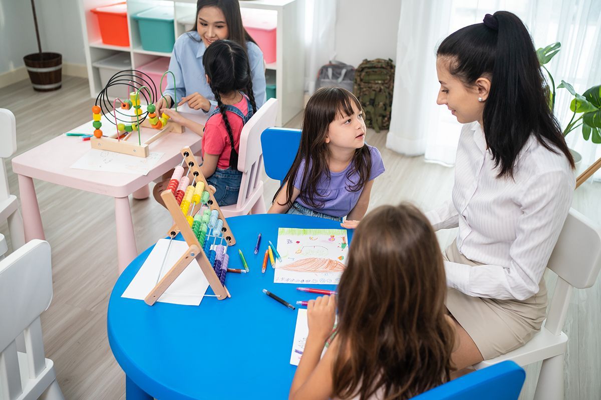 A woman is sitting at a table with three children.