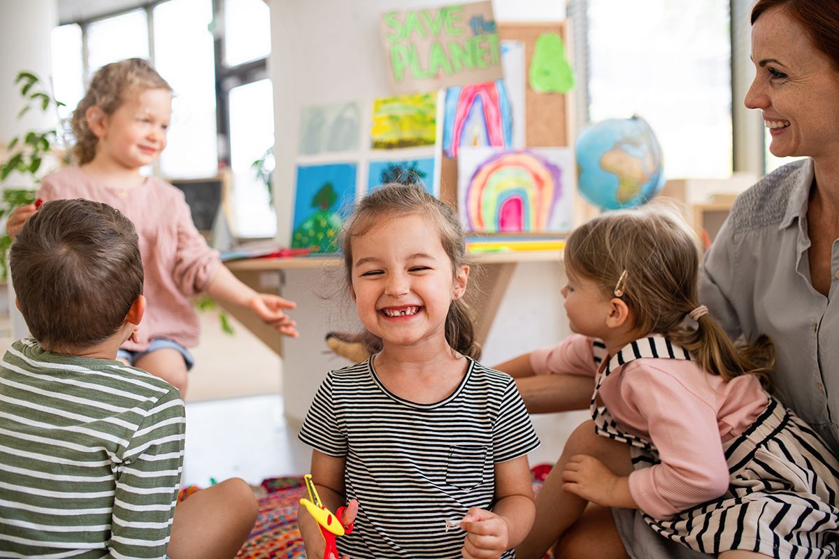 A woman is sitting on the floor with a group of children.