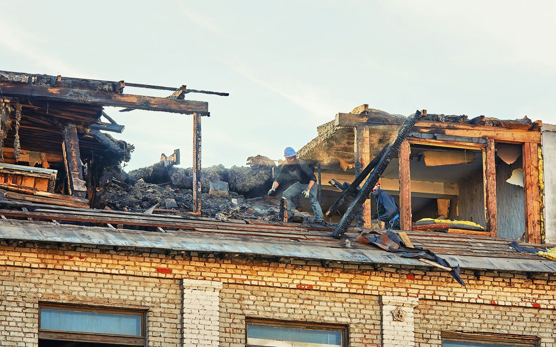 A man is working on the roof of an old brick building.