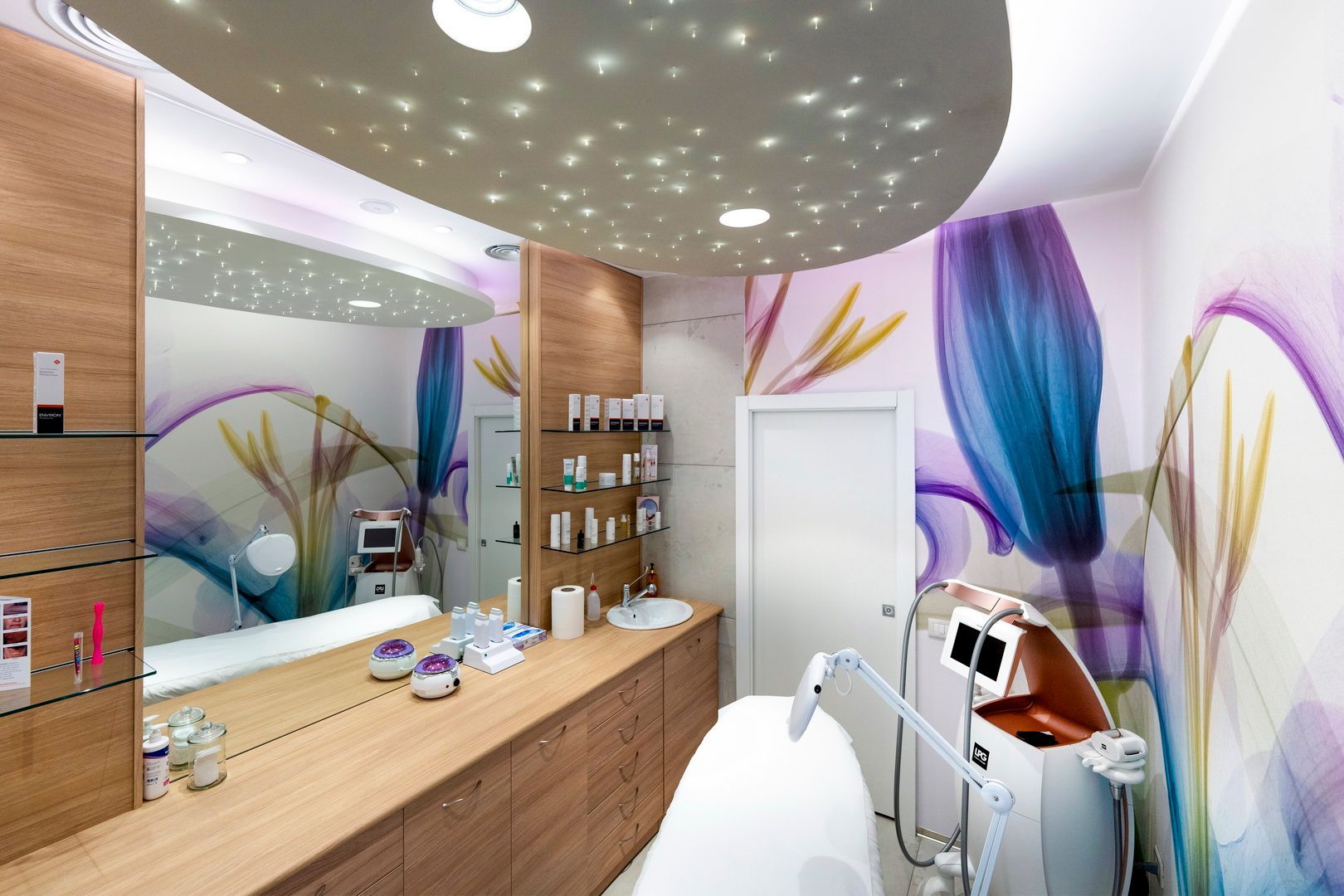 Luminosa clinica dentistica con coloratissimi quadri alle pareti, specchio, lavandino e poltrona odontoiatrica sotto un soffitto stellato.