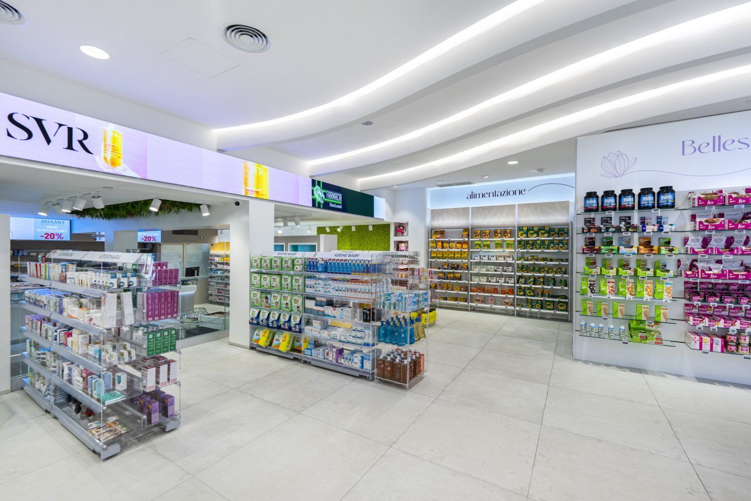 Luminoso interno di farmacia con scaffali di medicinali e prodotti per la salute sotto luci bianche a soffitto curve.