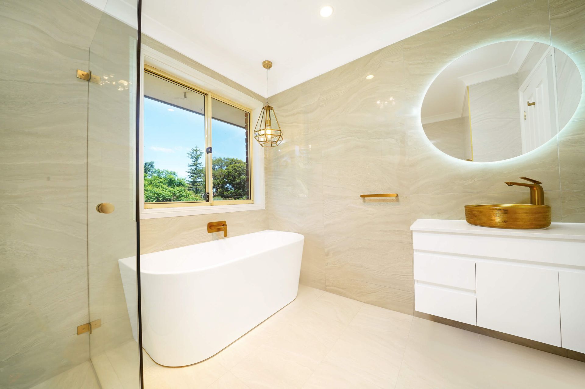 Modern white bathroom with farmhouse sink, brass faucet, built-in cabinets, and soft lighting