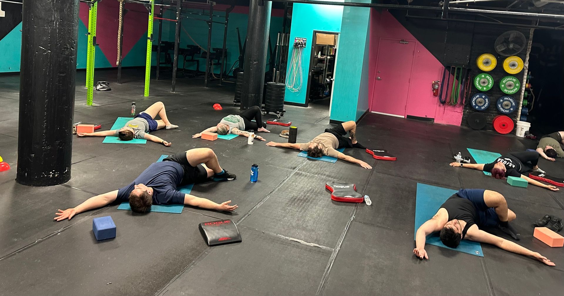 A group of people are laying on yoga mats in a gym.