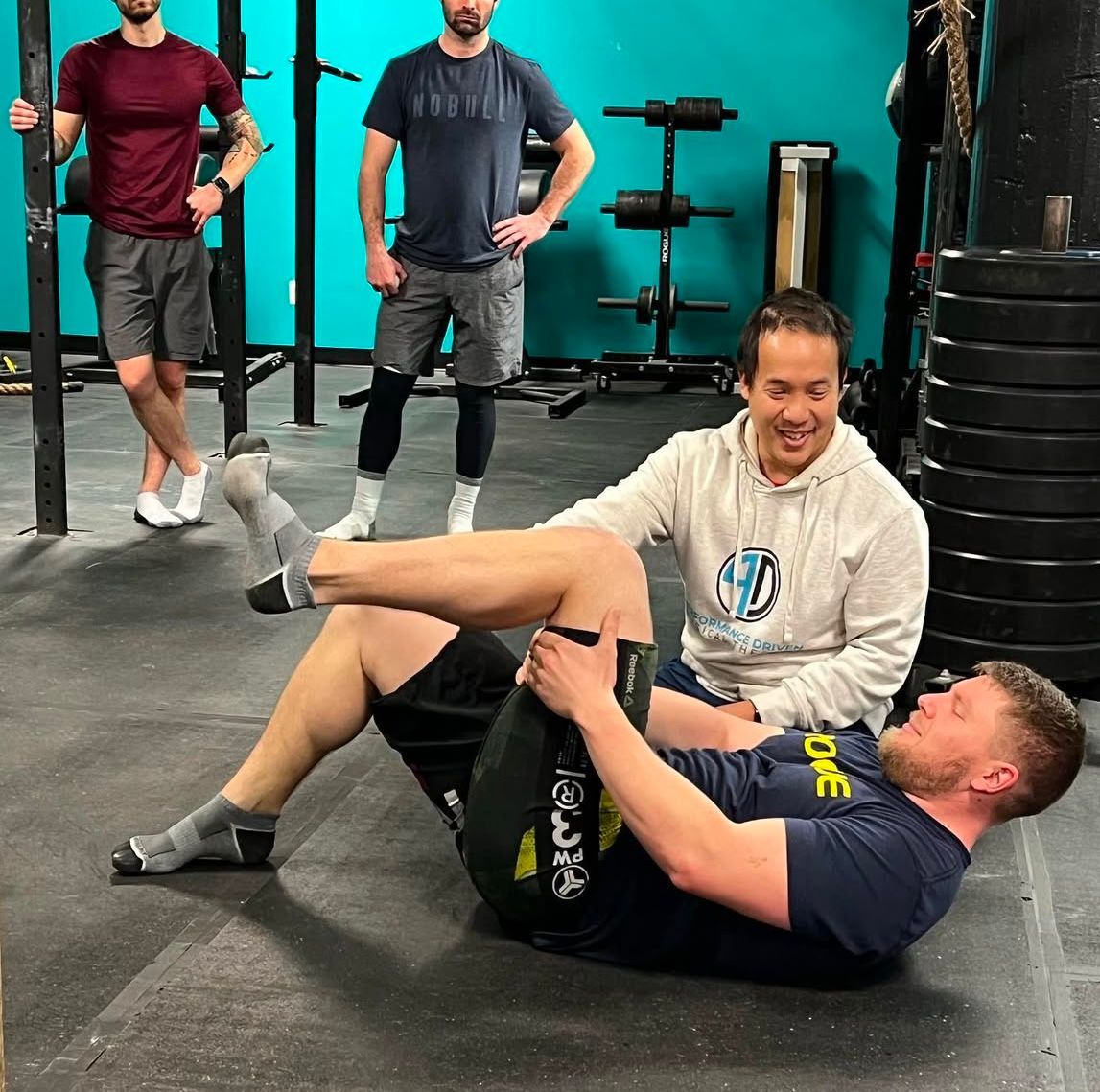 A man is laying on the floor in a gym with his legs crossed