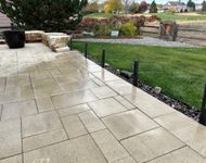 Partially paved patio with gray pavers and a person standing near a wooden post outdoors