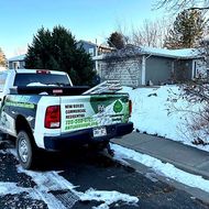 Snowy suburban street with a white pickup truck parked by a house and driveway.