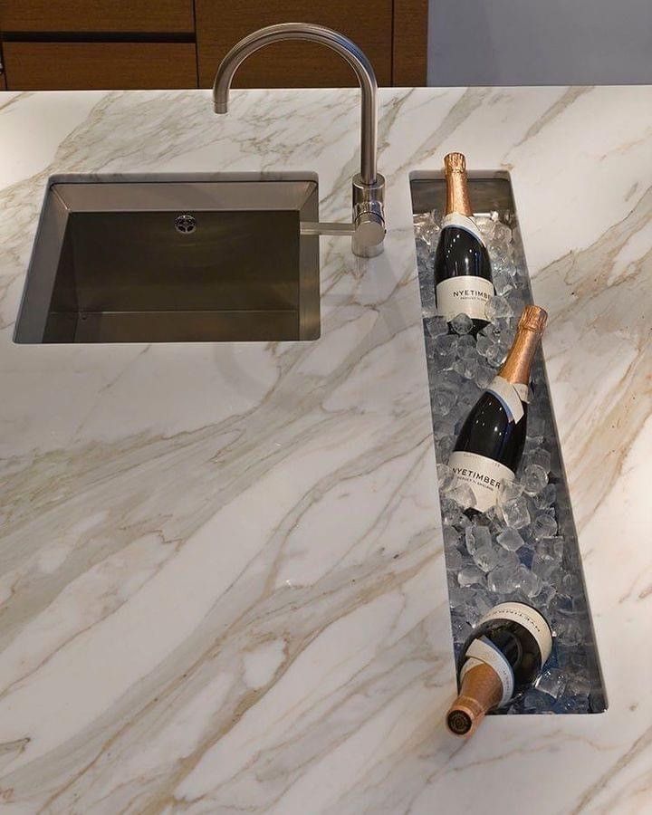A kitchen with white cabinets and marble counter tops