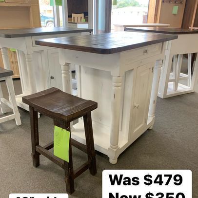 A wooden stool is sitting next to a white table.