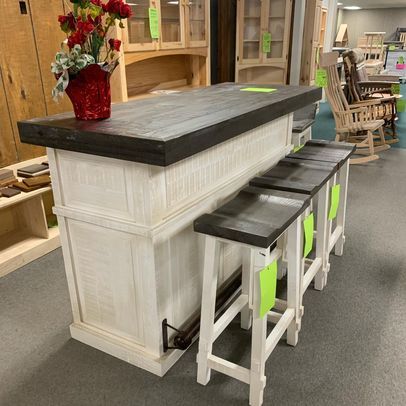 A bar with stools and a vase of flowers on top of it in a store.