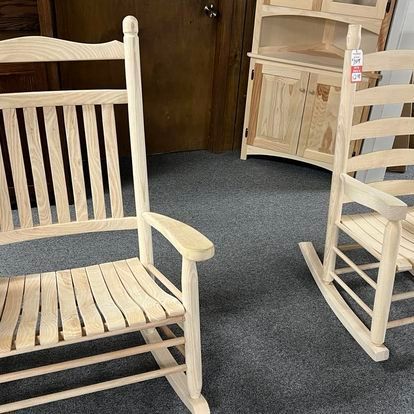 Two wooden rocking chairs are sitting on a carpeted floor in a room.