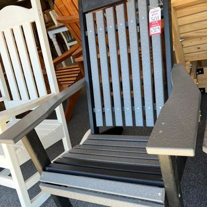 A black and gray rocking chair is sitting next to a white chair.