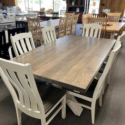 A wooden dining table with white chairs in a room.