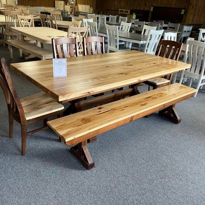 A wooden table with a bench and chairs in a room.
