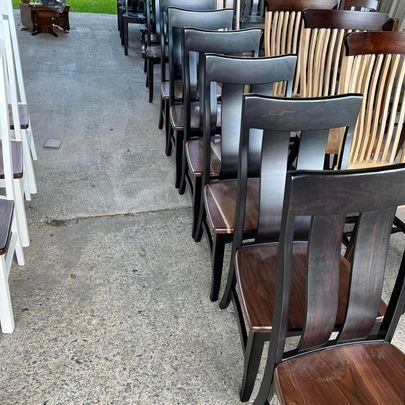 A row of wooden chairs are lined up on a sidewalk
