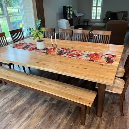 A wooden dining table with a bench and chairs in a living room.
