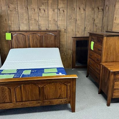 A bedroom with a wooden bed , dresser , nightstand and mattress.