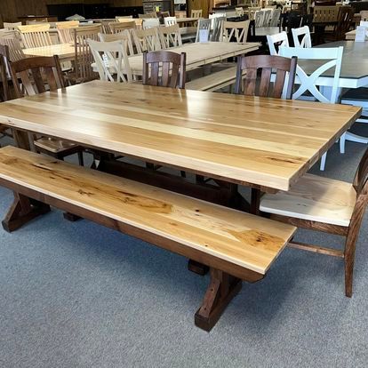 A wooden table with a bench and chairs in a room.