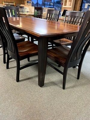 A wooden dining table and chairs are sitting on a carpeted floor in a room.