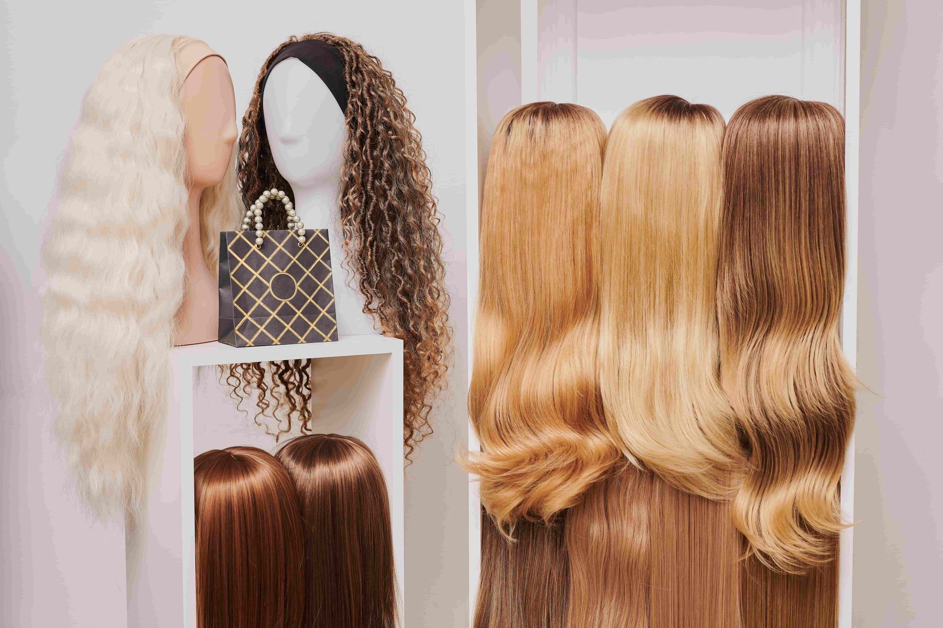Synthetic wigs displayed on mannequin heads, in blonde, brown, and curly styles on shelves