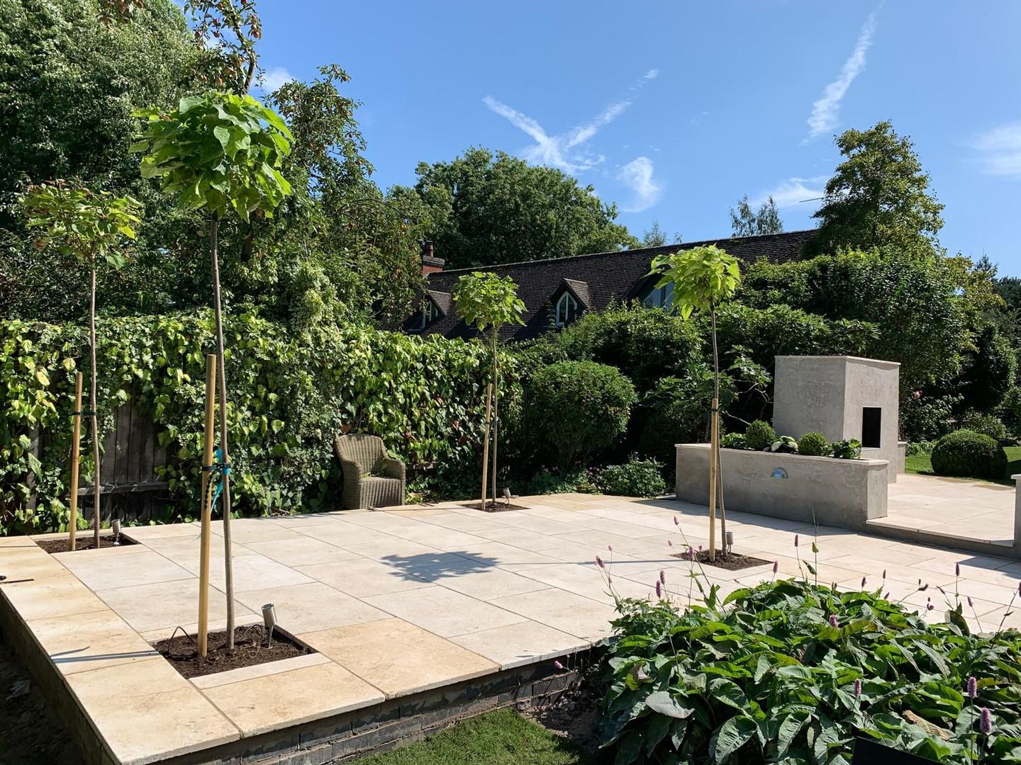 A patio with trees and a bench in a garden