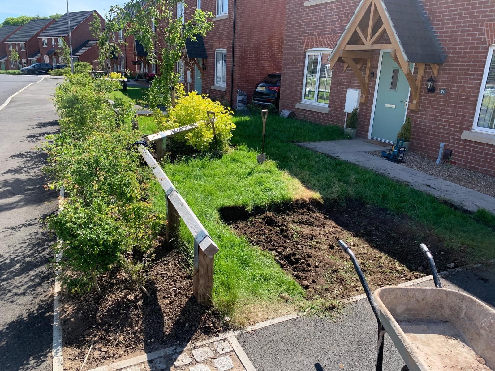 A wheelbarrow is parked in front of a brick house.