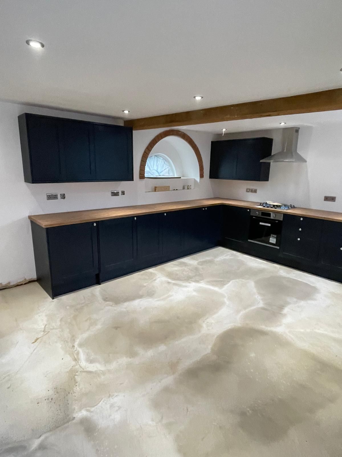 A kitchen with black cabinets and a concrete floor.