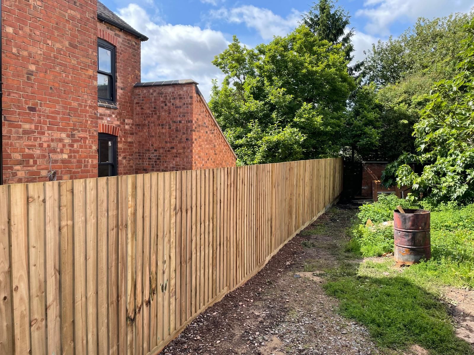 A wooden fence is surrounding a brick house.