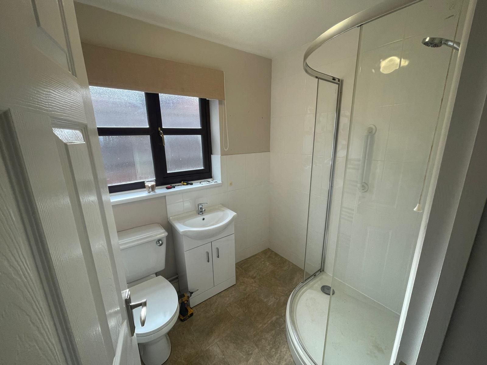 A bathroom with a toilet , sink and shower.
