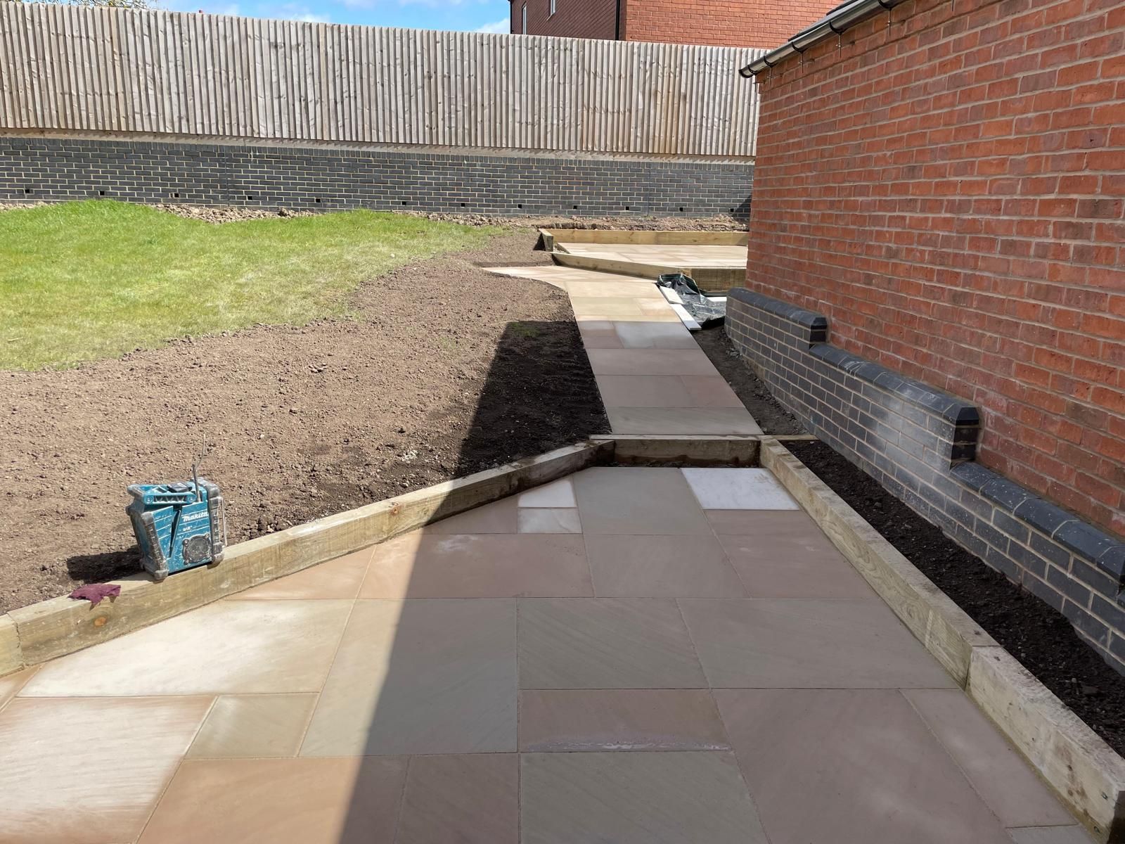 A walkway leading to a brick building with a fence in the background.