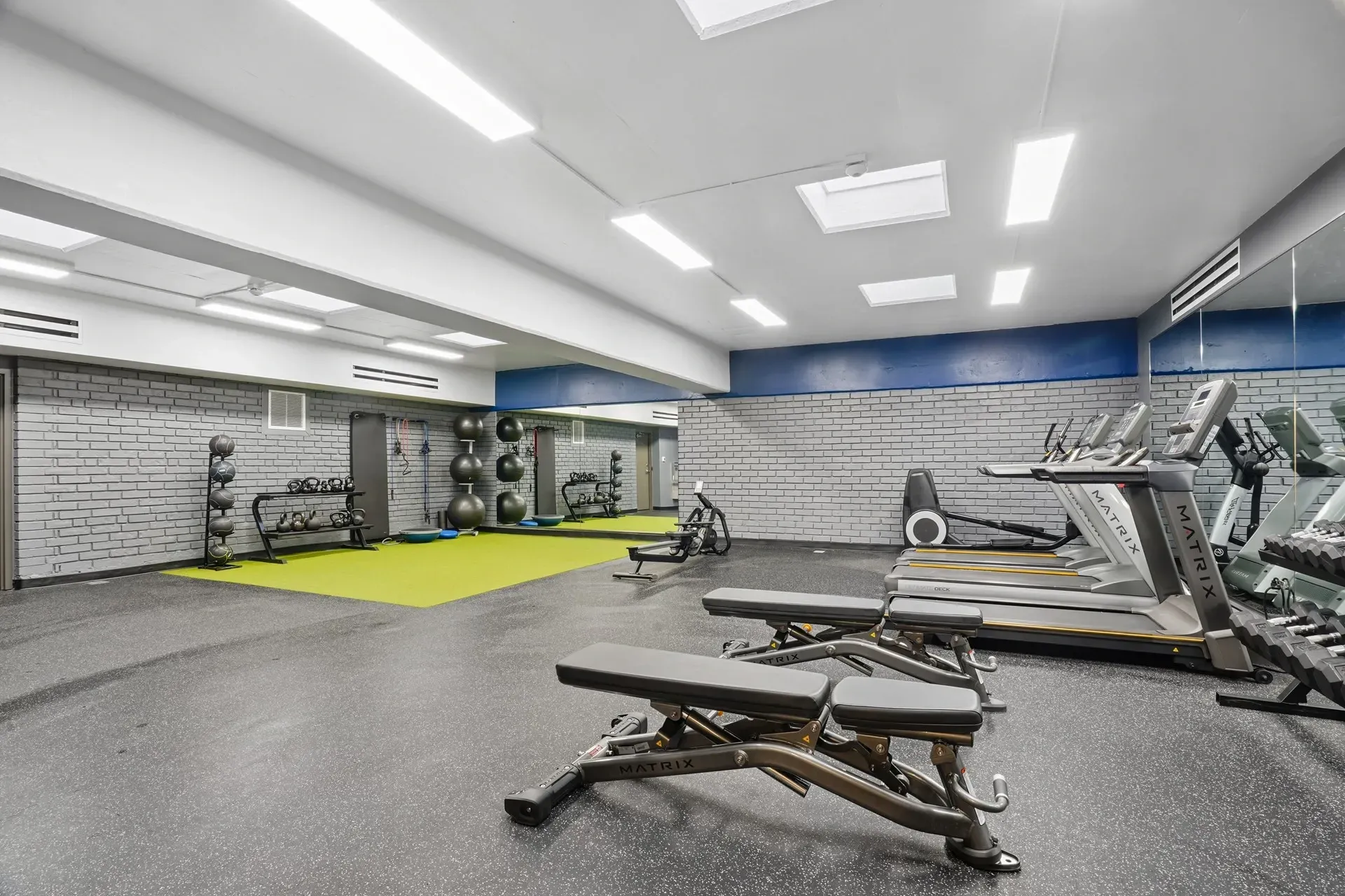 Fitness center with treadmills, weight benches, free weights, and exercise balls.