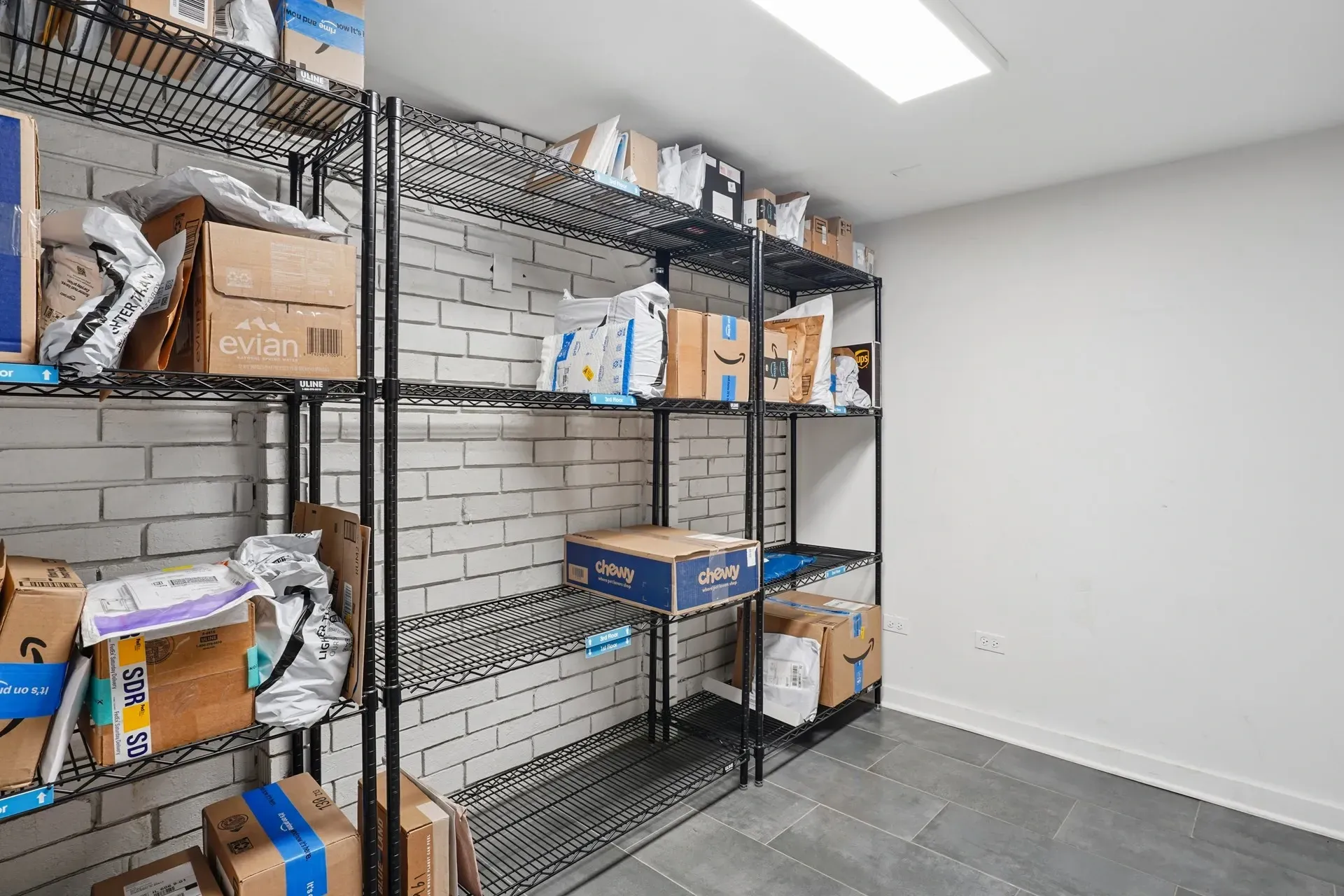 Package room with shelving units filled with boxes and packages.