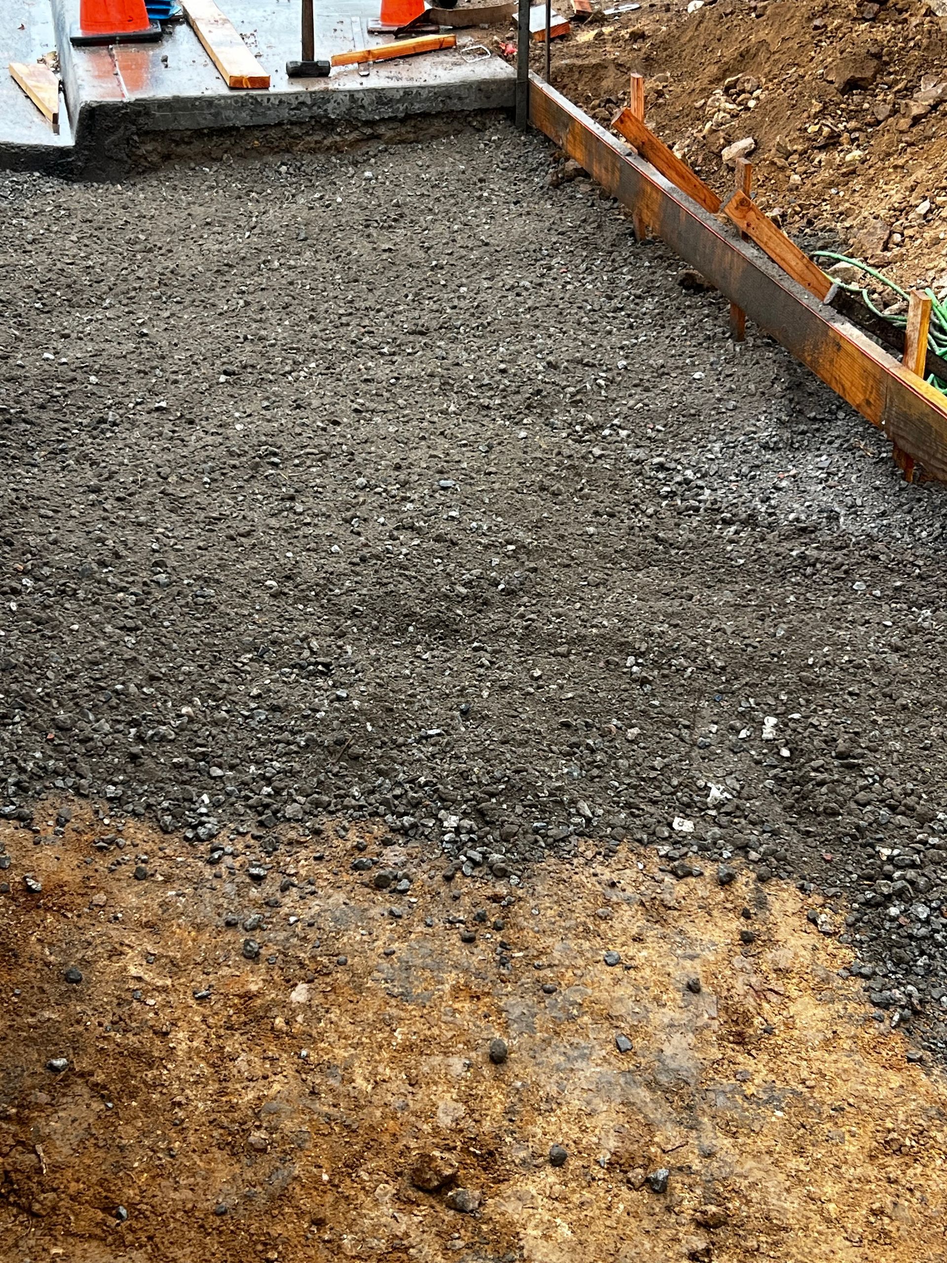 A construction site with gravel and concrete being poured.