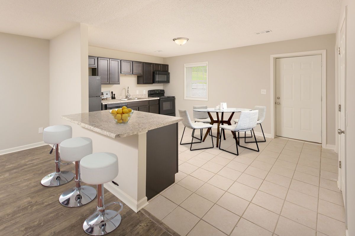 Kitchen with a granite-topped island, three white bar stools, and a small dining table with four chairs on tiled flooring.