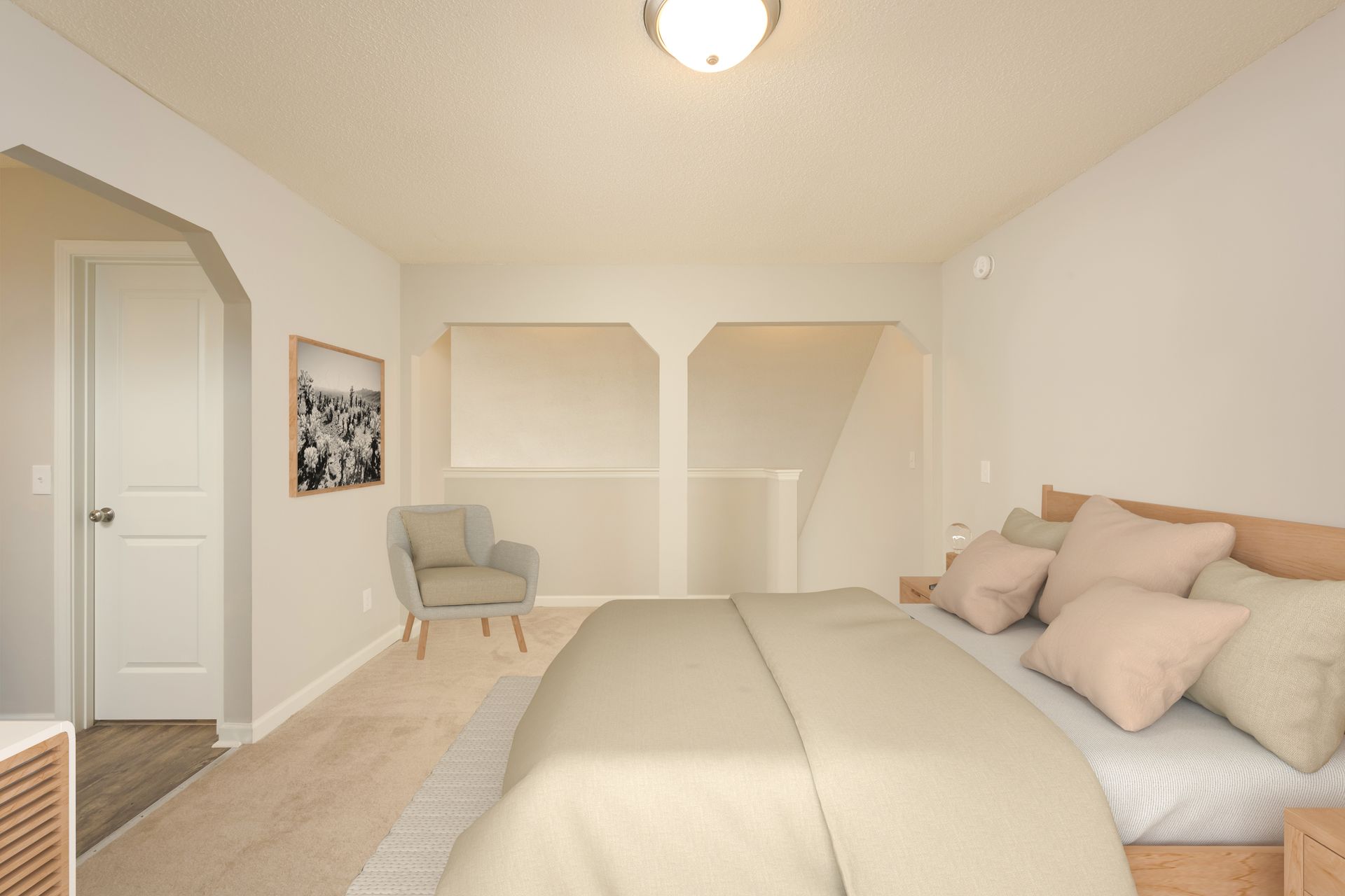 A bright bedroom featuring a bed with neutral linens, a grey armchair, and a doorway, all in soft beige tones.