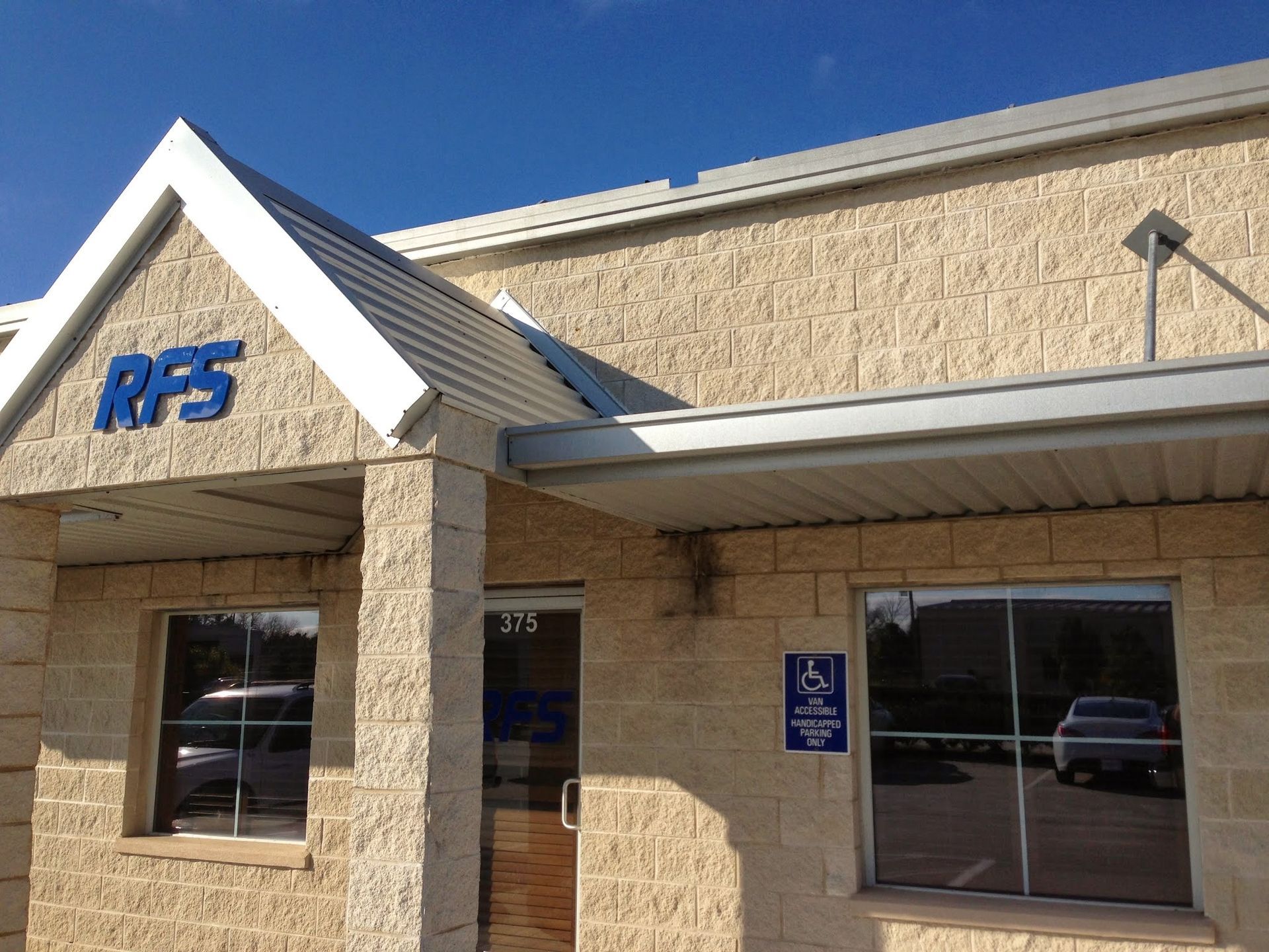 Building with RFS logo, accessible entrance, and reflective windows under a blue sky.