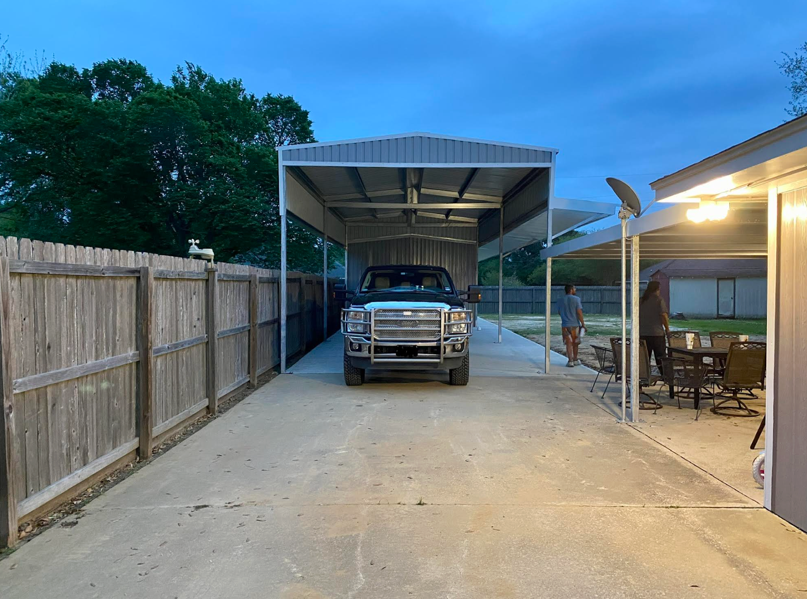 Metal carport in a work area with support beams, and a corrugated roof.