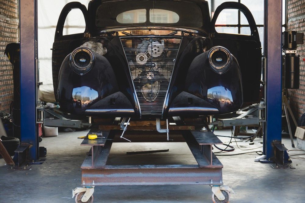 A Black Car is Sitting on a Lift in a Garage — Forster Mechanical Repairs & Servicing In Forster, NSW