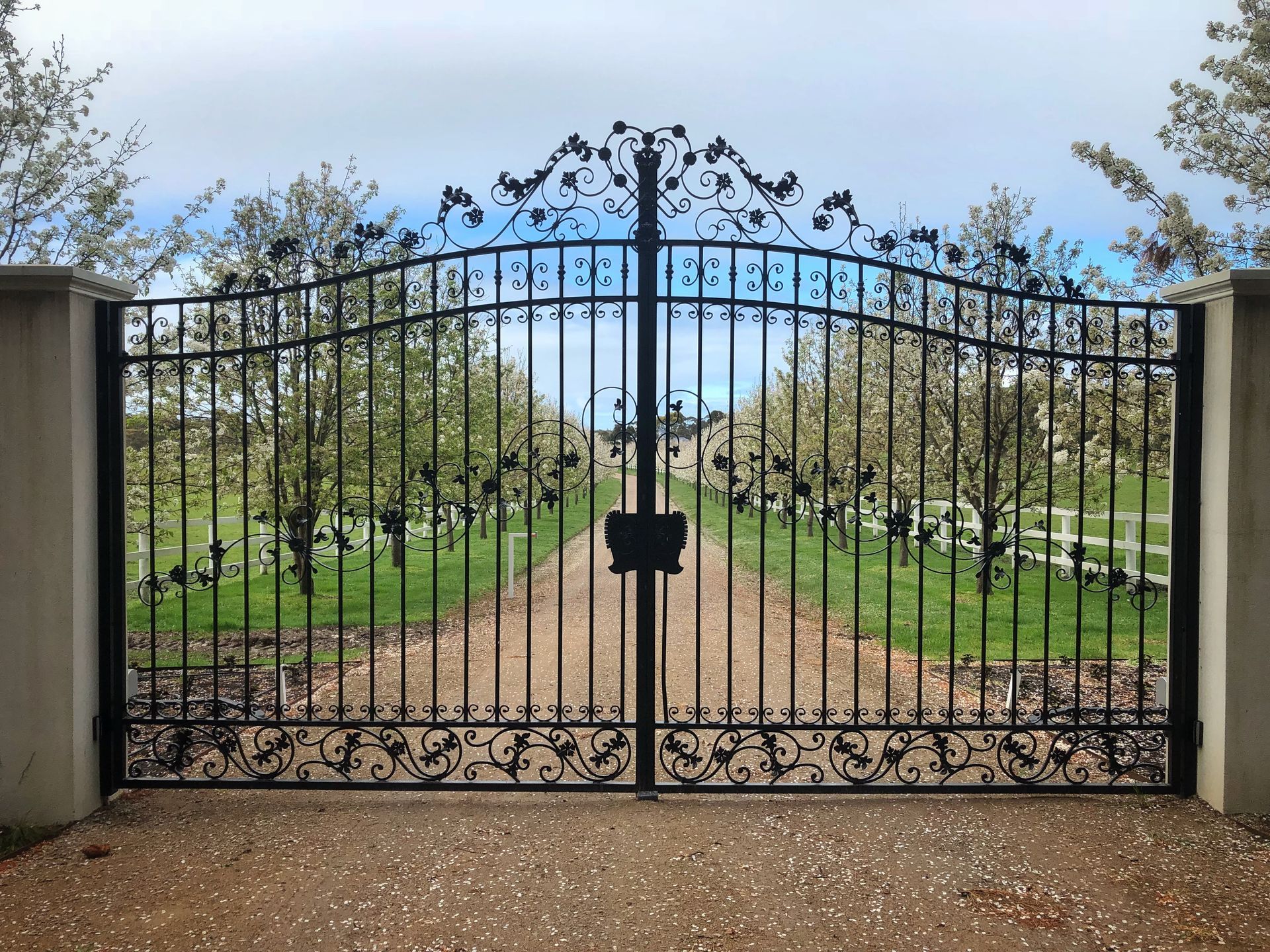 A wrought iron gate leading to a dirt road