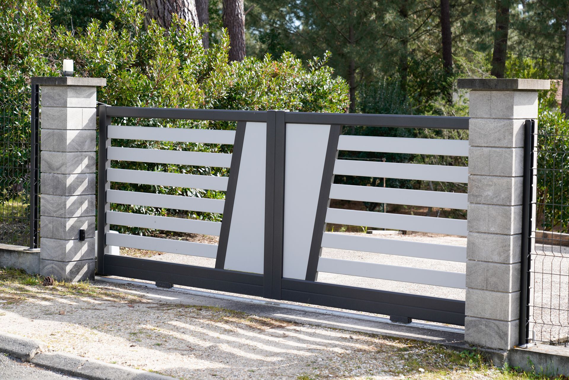 A black and white gate is open to a driveway
