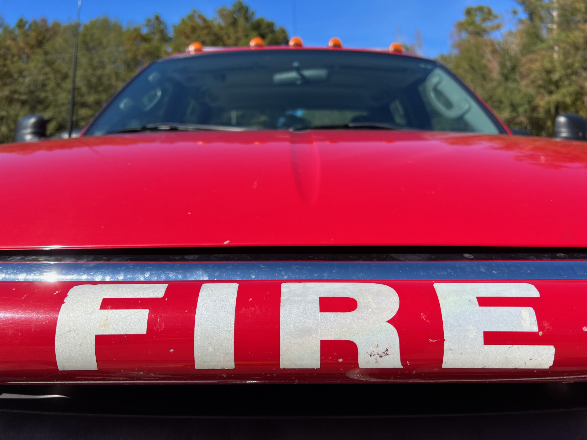 The hood of a red fire truck with the word fire painted on it.