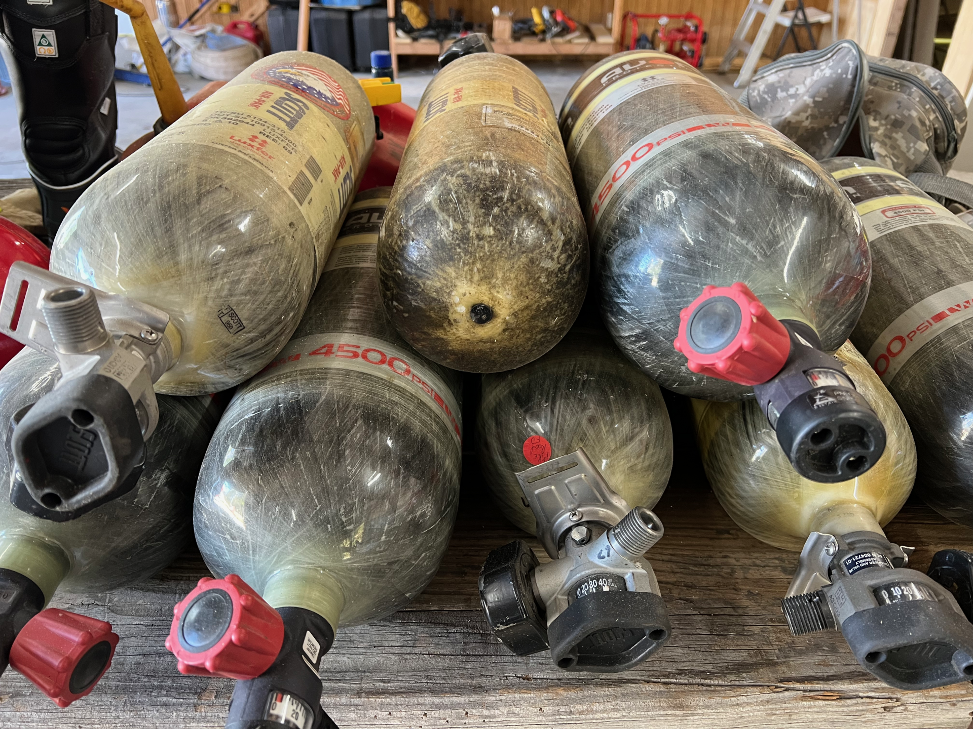 A bunch of air tanks are stacked on top of each other on a wooden table.