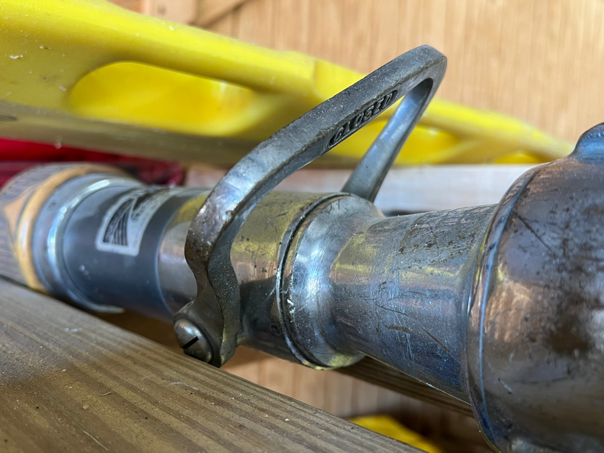A close up of a metal firehose nozzle with a handle attached to it.